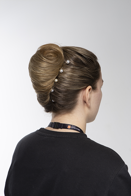 Back of student's head showing a formal bun with four clips