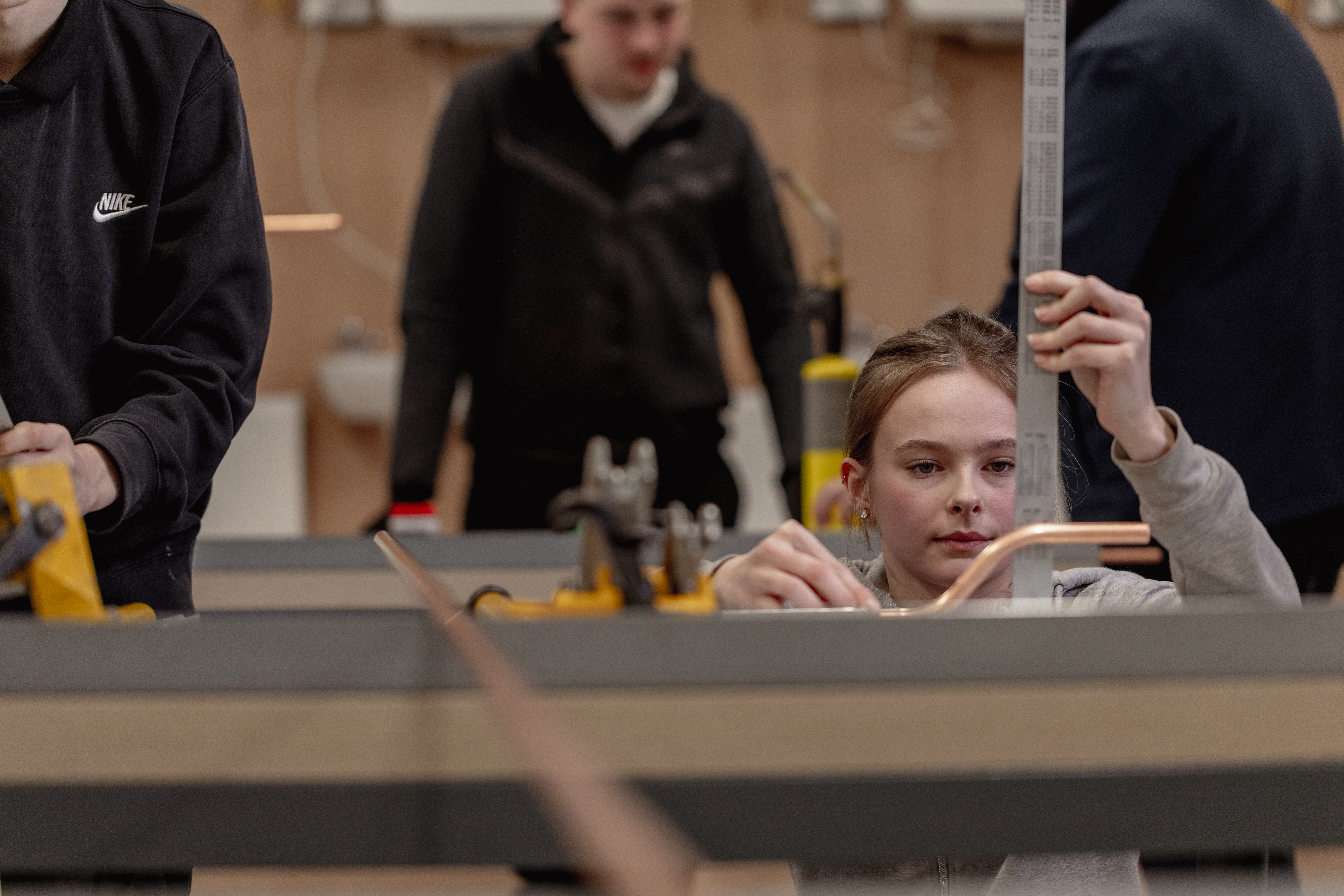Student sat at a desk writing with a laptop open next to him