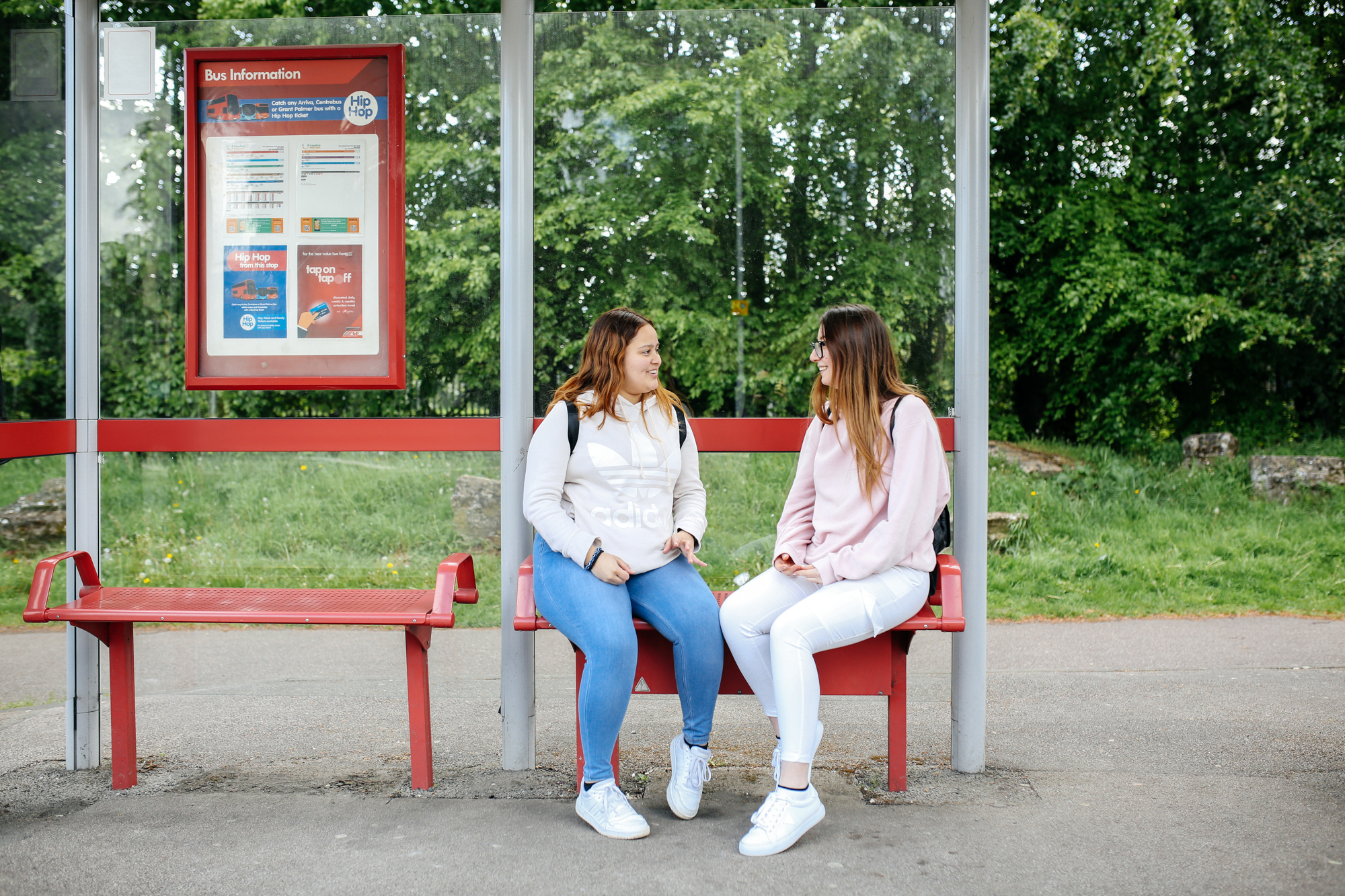 Two girls sat at a bus stop