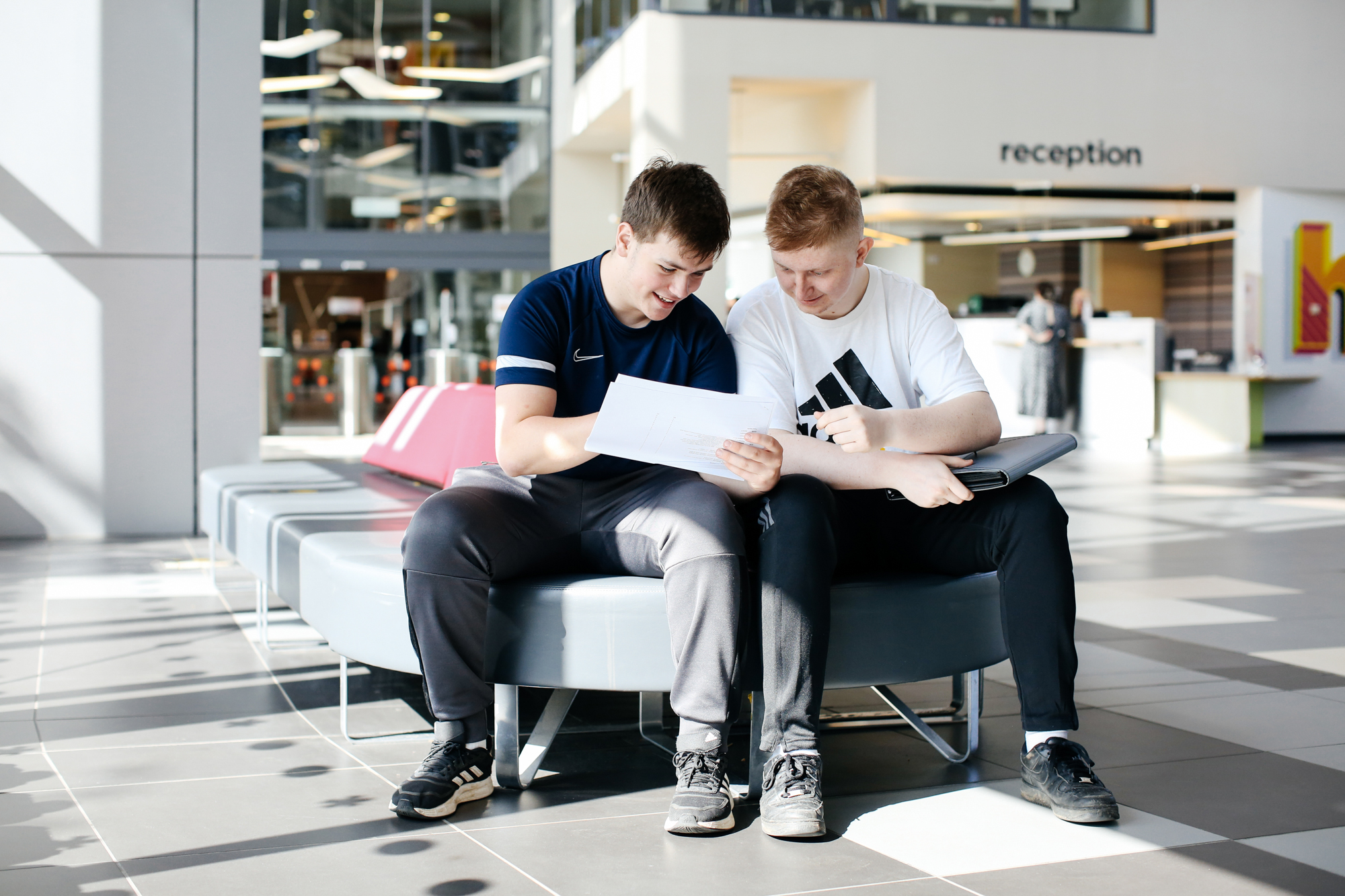 Two boys sat down looking at a piece of paper