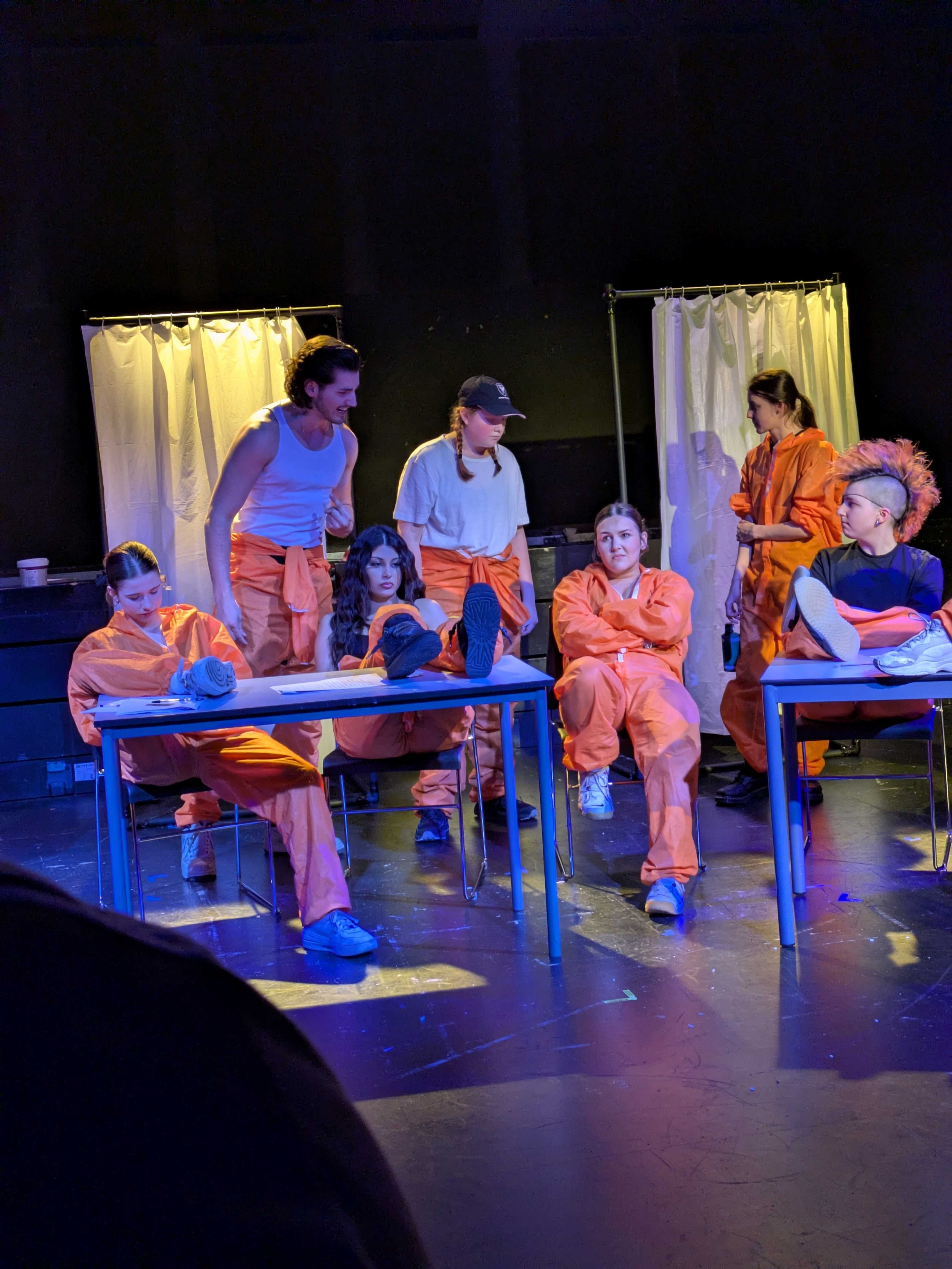 Students sit down on stage talking 