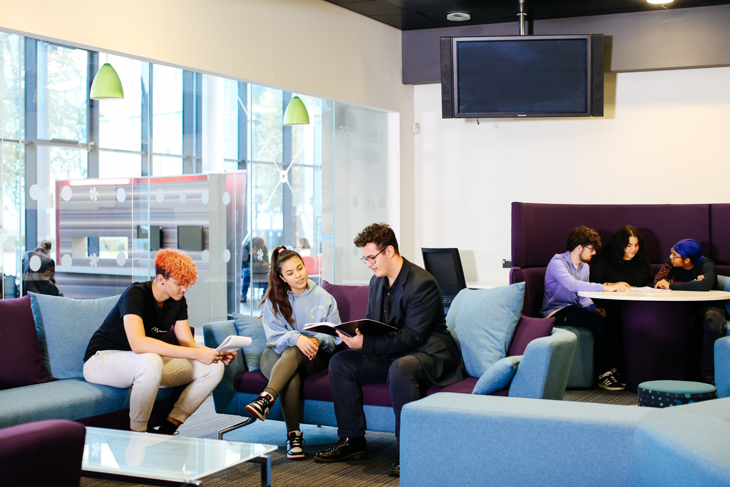 Two boys and a girl chatting on a sofa in the Business Lounge chatting