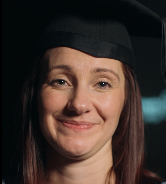 Sam smiling looking at the camera with her graduation hat on