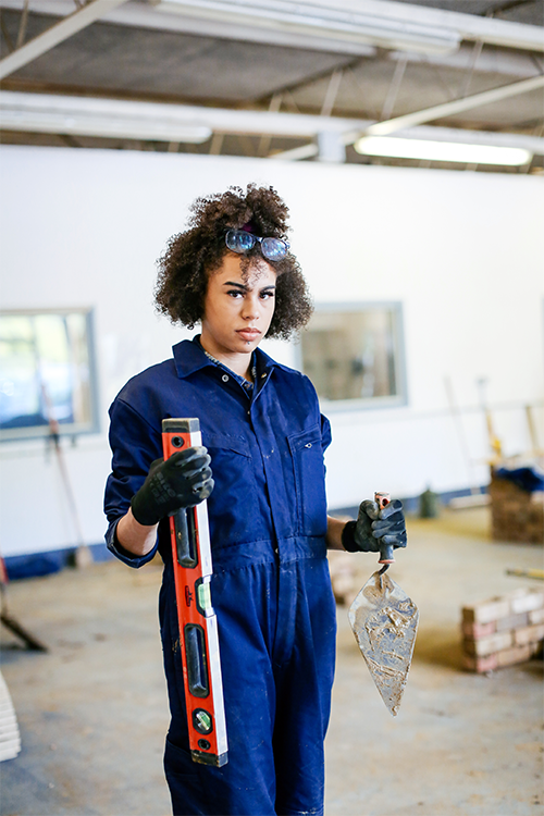 Student holding a trowel and spirit level measurer