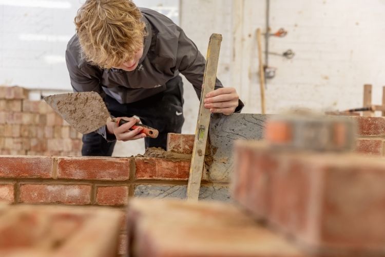 Student measuring brick wall
