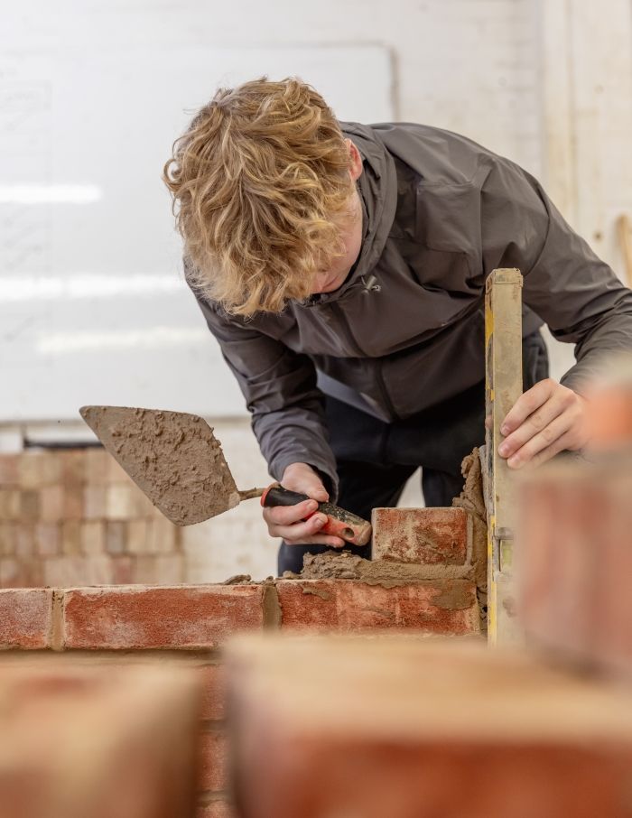 Student working with cement and bricks