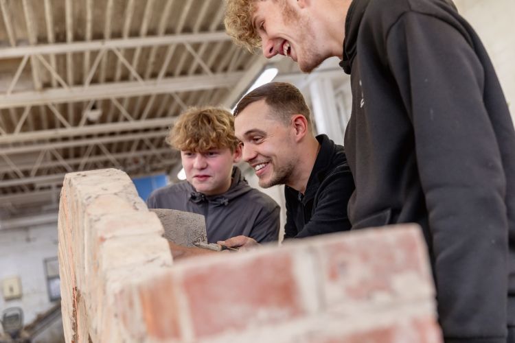 Tutor showing students how to do bricklaying