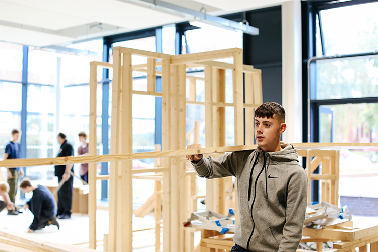 Student carrying a piece of wood