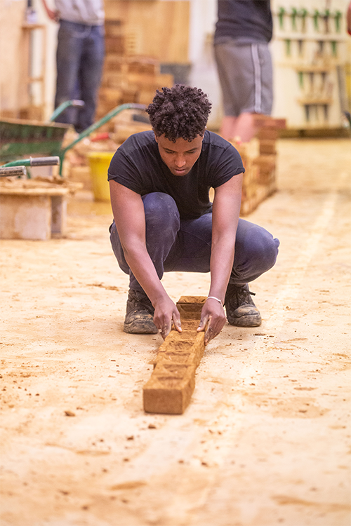 Student laying bricks to start a brick wall