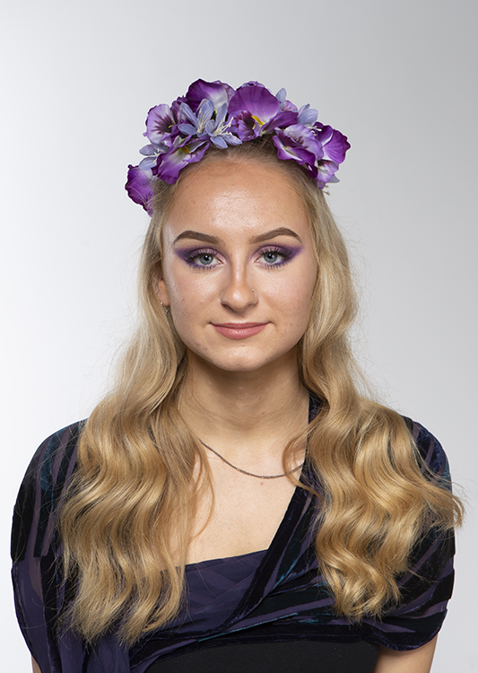 Student facing camera wearing a flower headband with glam makeup on