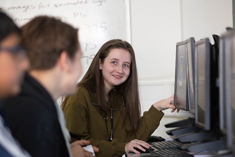 Student smiling pointing at computer screen