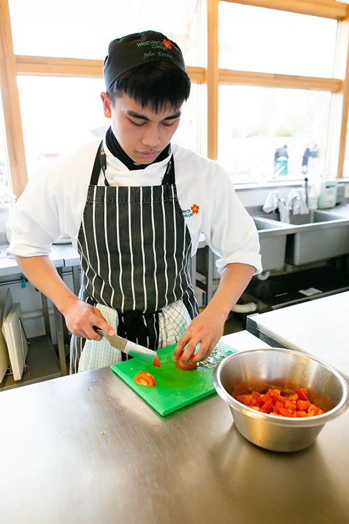 student chopping tomatoes