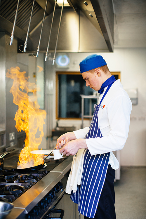 Student cooking food in a frying pan