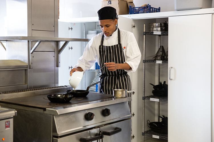 Student pouring food into a pan