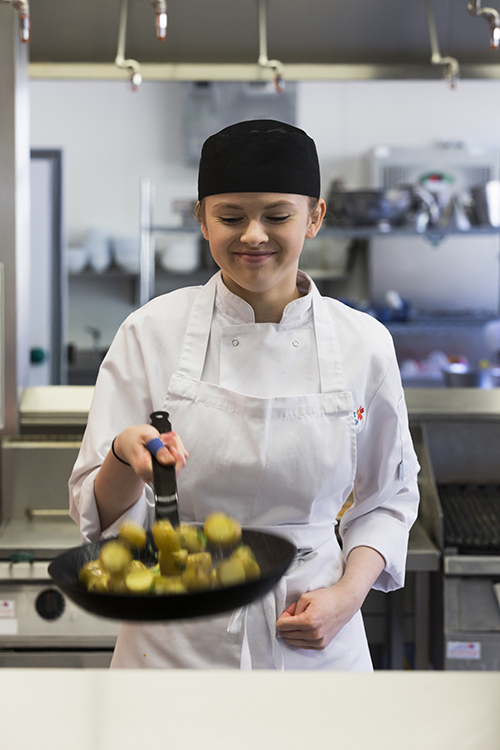 Student cooking food in a frying pan