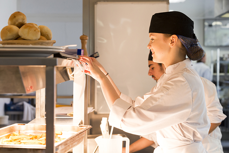 Student looking at food orders in kitchen