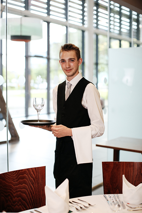 student holding a tray with a glass on it