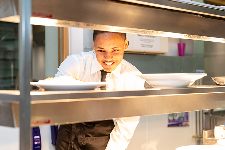 student collecting plates from the kitchen