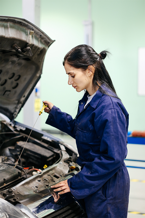 Student checking oil levels of a car