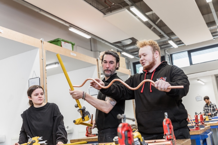 Tutor working with a student on a plumbing project