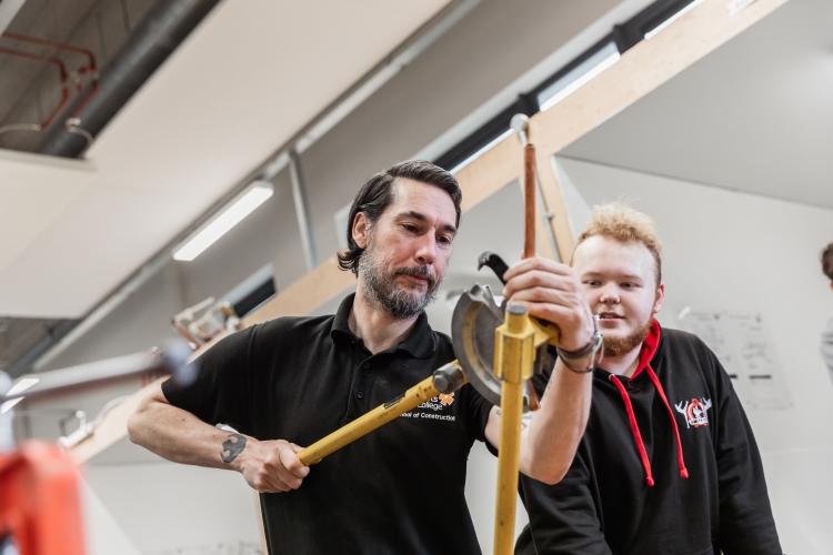 Tutor working with student on a plumbing project