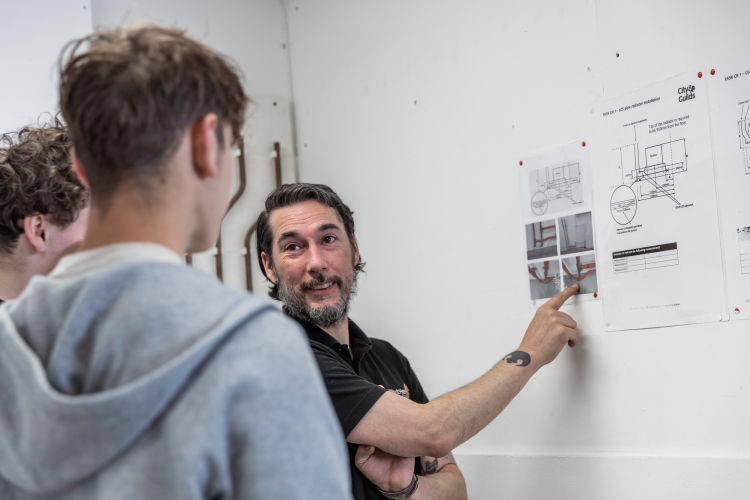 Tutor showing students paper that is on a wall