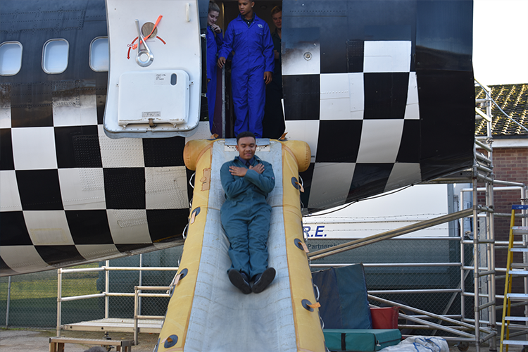 Student sliding down a plane safety slide