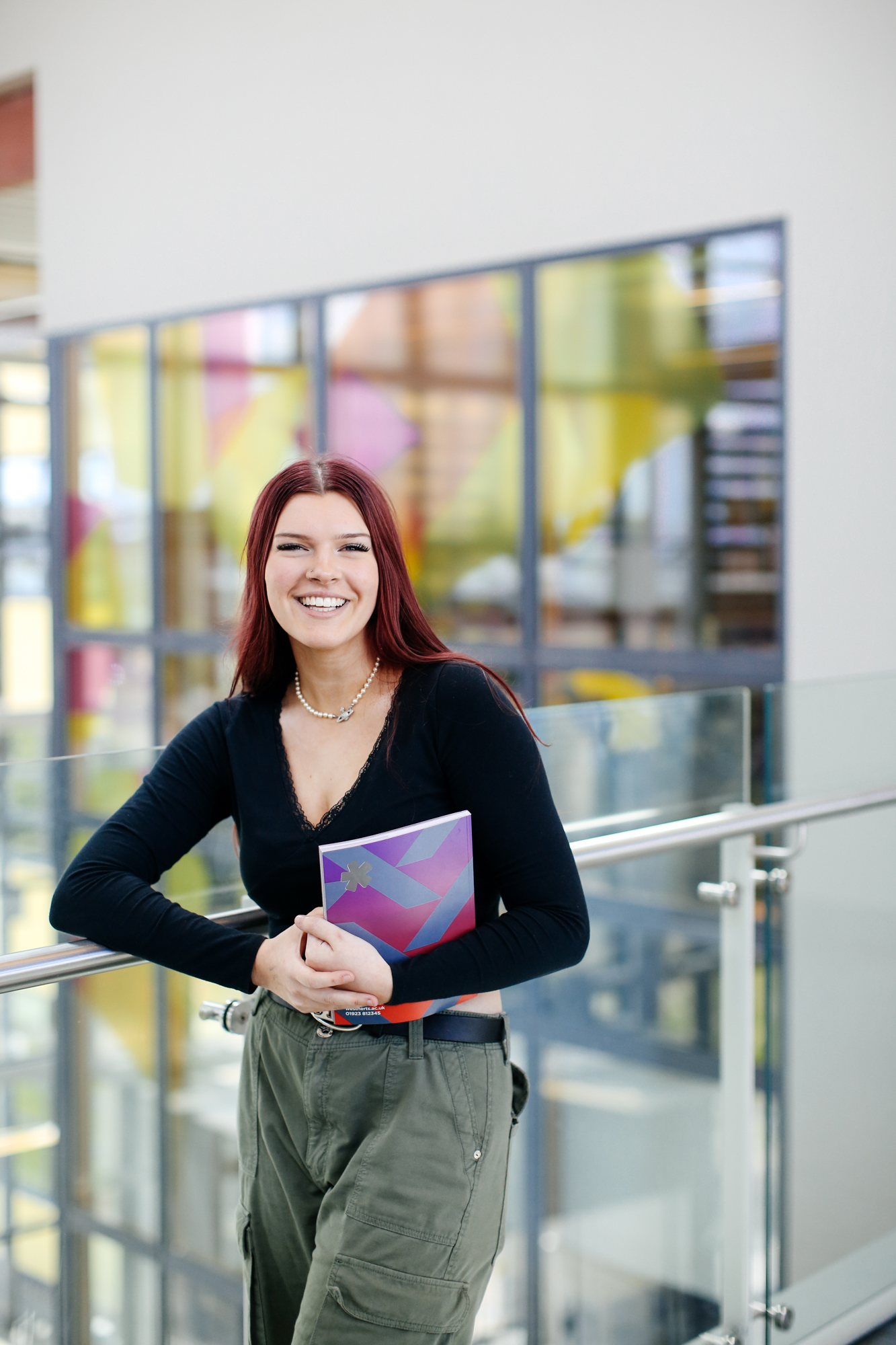 Student standing smiling holding a book