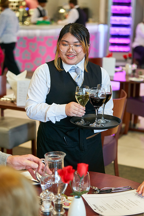 Hospitality student placing drinks on table