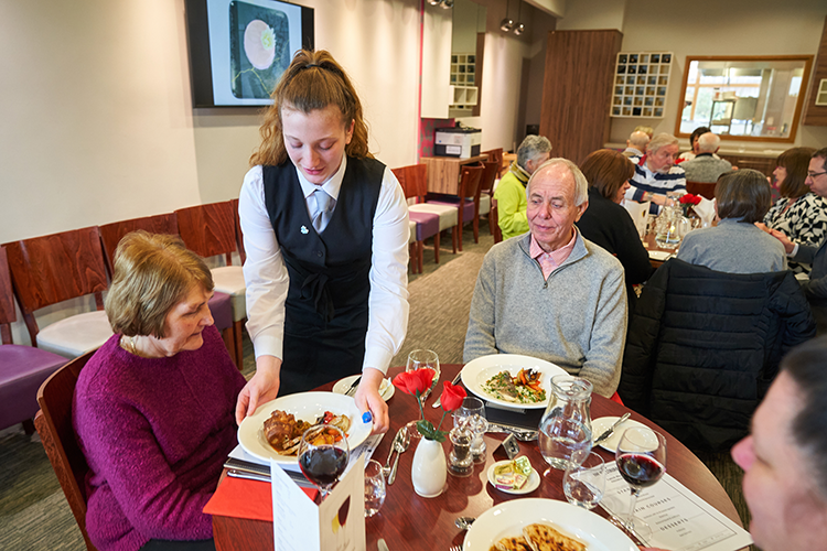 Hospitality student plating food on table 