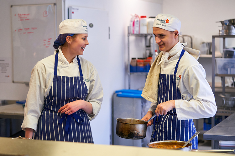 Professional cookery students laughing in kitchens