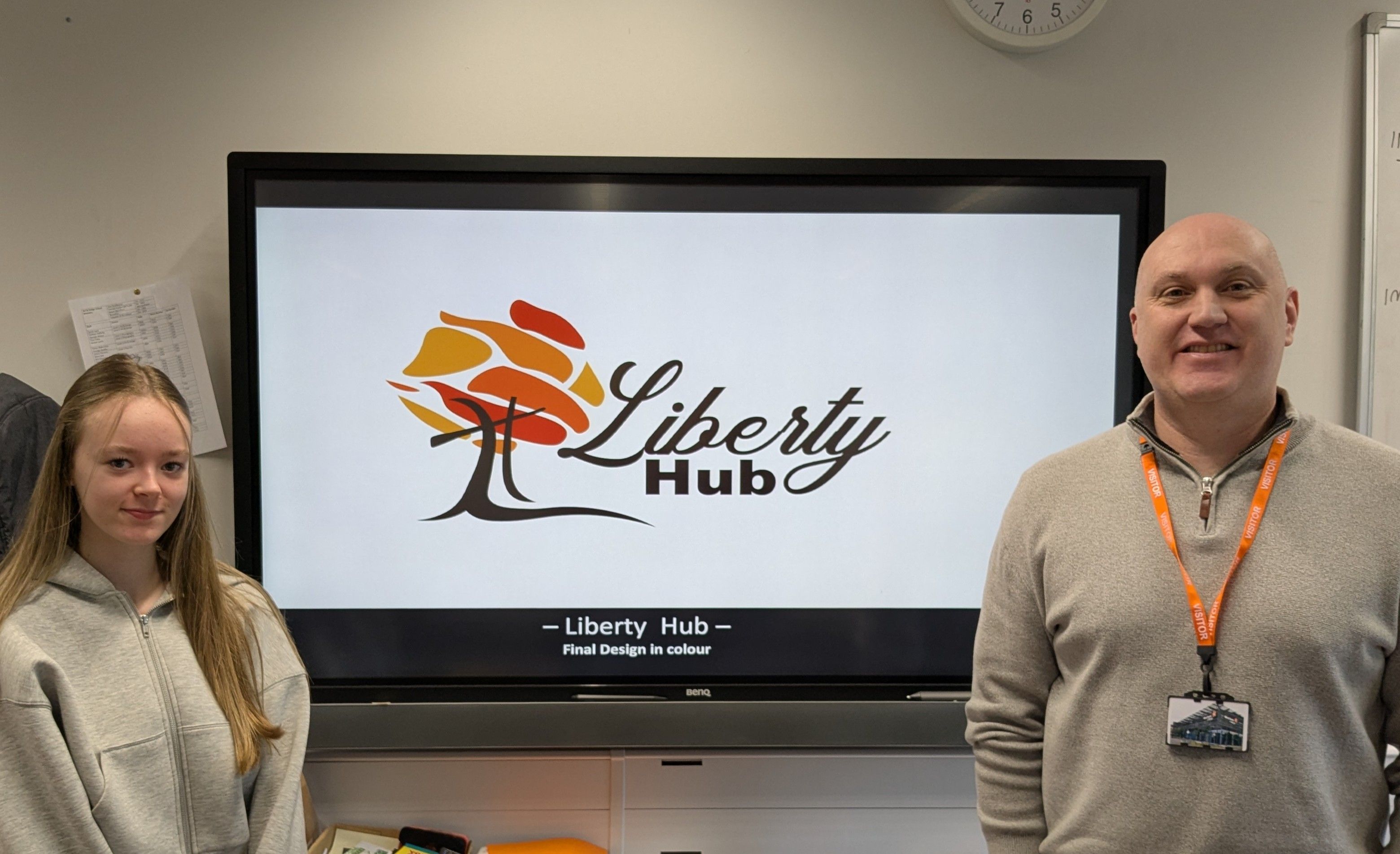 Winning student and employer stood in front of screen with winning design