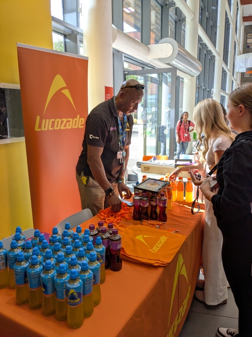 Students talking to an exhibitor at a Lucozade branded table