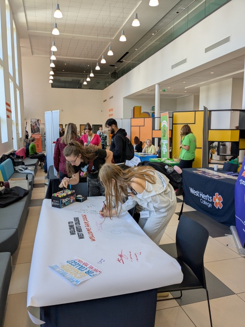 Students writing on welcome fair poster which was placed on a table