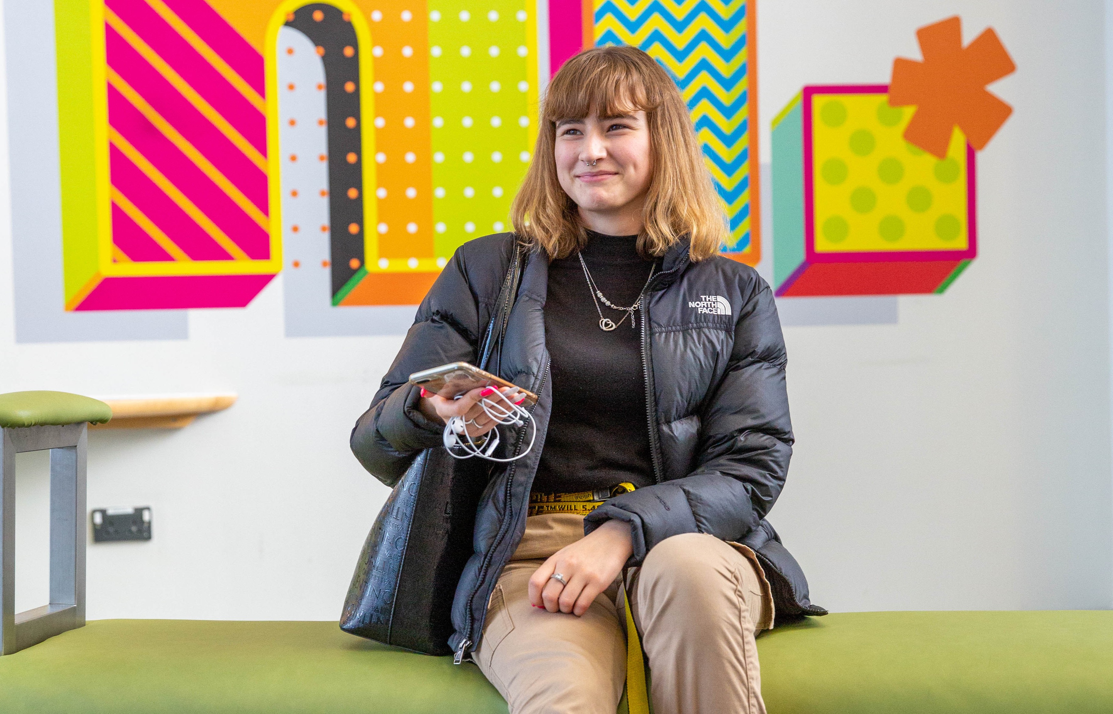 Girl sitting on a bench smiling with her phone in her hand
