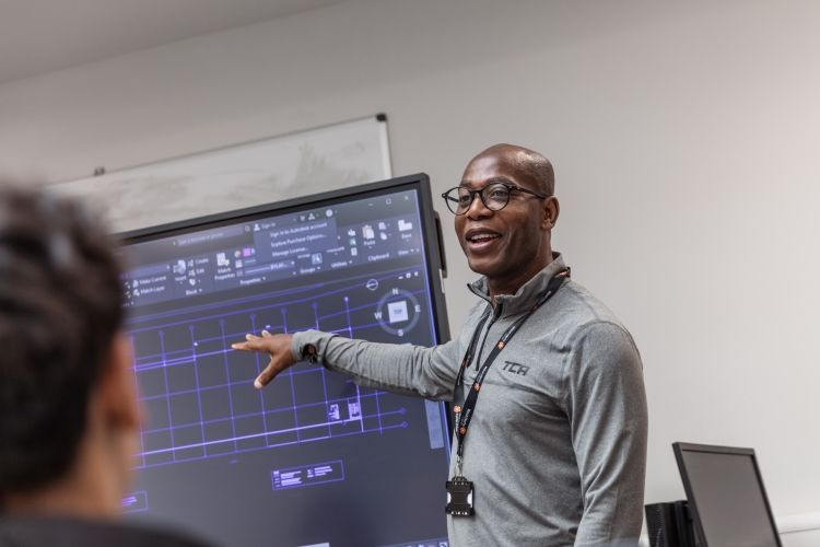 Tutor pointing to a screen to show students information during a lesson