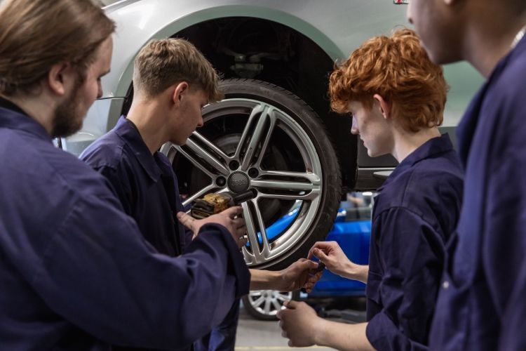 Four students working on fixing a care tyre